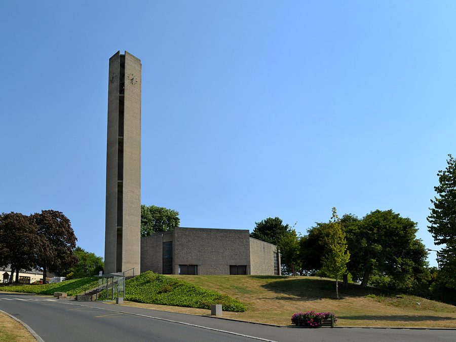 Südostansicht der Kirche Notre-Dame-de-la-Nativité in Cahagnes mit schlankem Betonglockenturm
