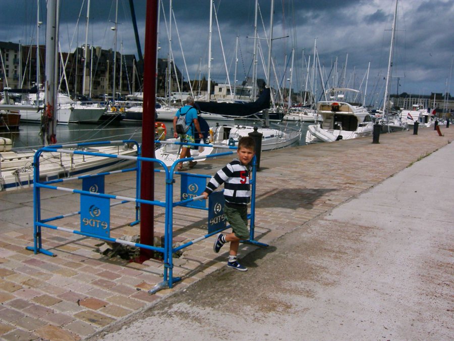 Segelboote im Hafen der Normandie mit einem Kind am blauen Geländer